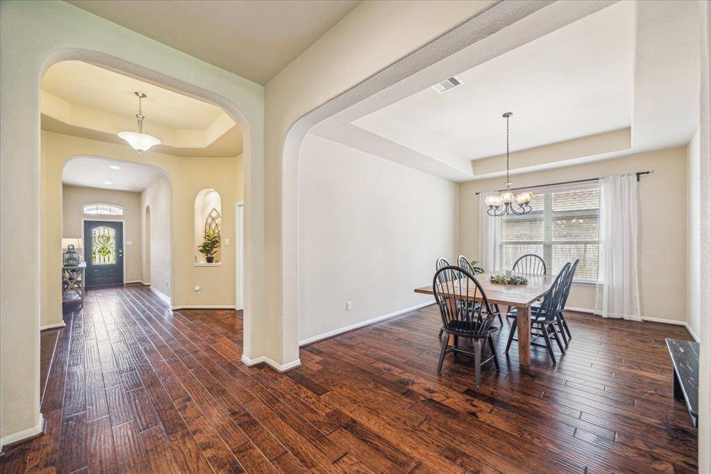 Your friends and family are going to love breaking bread with you in this elegant formal dining room with wood flooring, neutral paint, a raised tray ceiling, stylish chandelier, and ample space for your banquet table and sideboard.