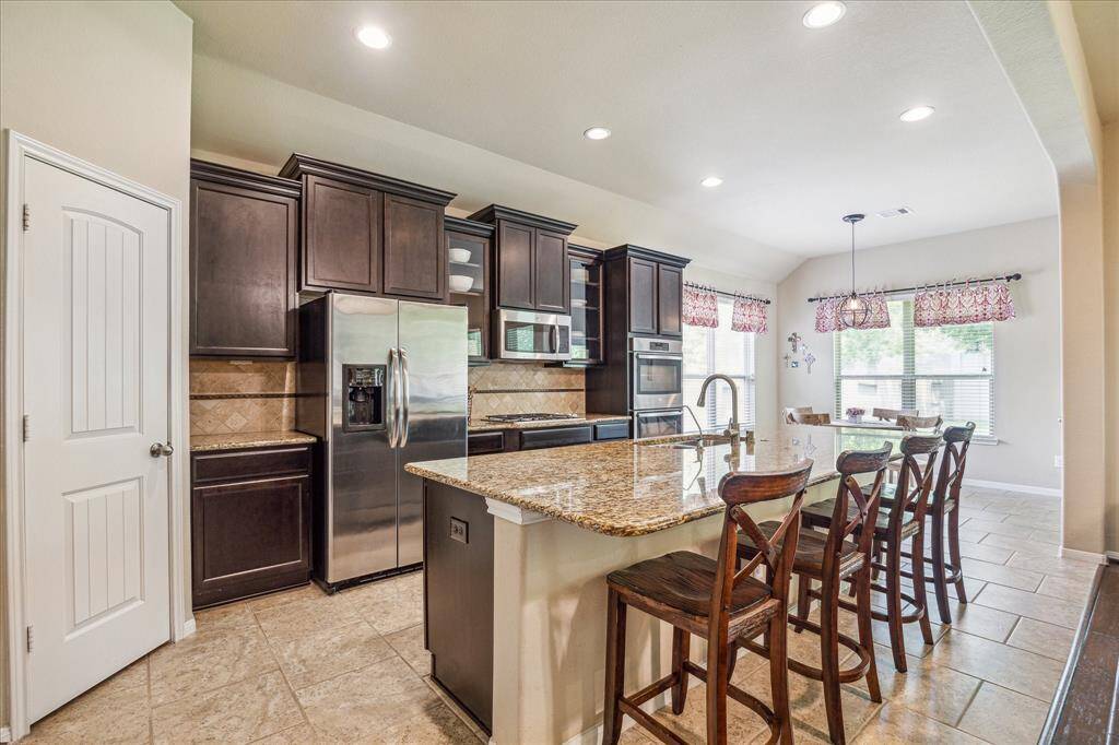 This immaculate kitchen is the perfect place to show off your culinary skills, with gorgeous granite countertops, designer tile backsplash, abundant cabinetry, sleek stainless steel appliances, a spacious walk-in pantry, and an oversized island with bar seating.