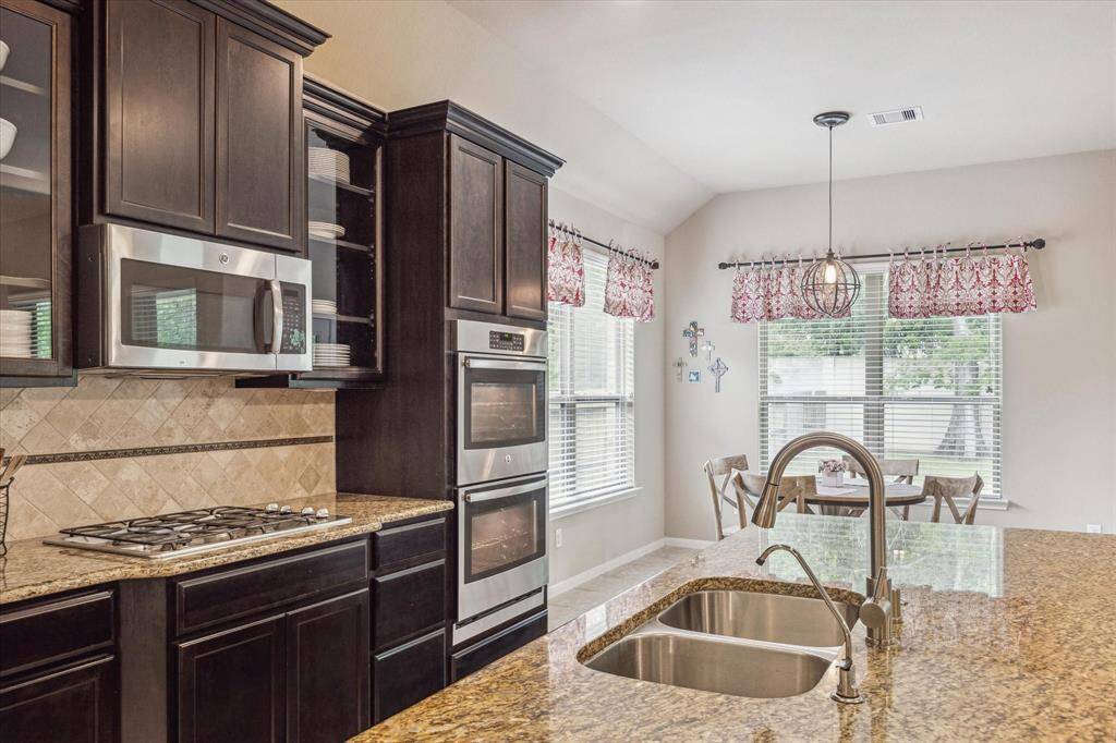 The kitchen features sleek stainless steel appliances, including built-in double ovens, a microwave, gas cooktop, and automatic dishwasher. It's the perfect setup for everything from midnight snacks to holiday feasts.