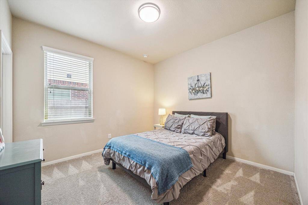 With four spacious bedrooms and three full bathrooms, there’s always room to welcome guests in comfort. This particular bedroom is conveniently located near the utility room and a full bath, ideal for visitors or multi-generational living.