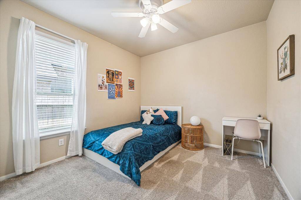 Another inviting guest room showcases fresh neutral finishes, including updated carpet, soft paint tones, a cooling ceiling fan, a spacious closet, and easy access to a beautifully updated full bathroom.