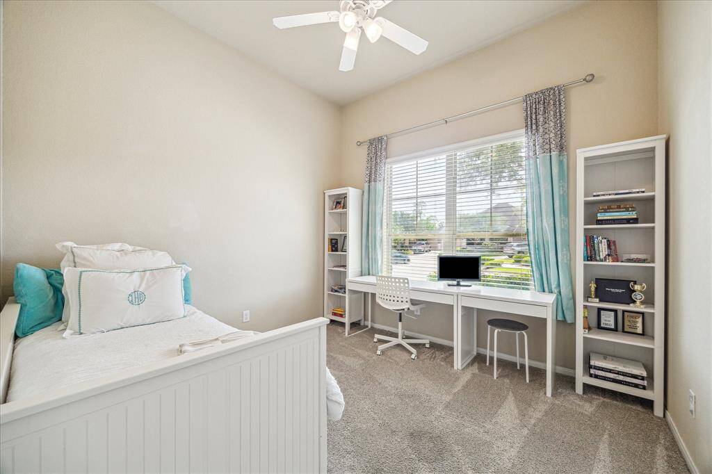 This comfortable guest bedroom features fresh carpet, neutral paint, a cooling ceiling fan, a spacious closet, and convenient access to the nearby full bathroom offering a restful space for family or overnight visitors.
