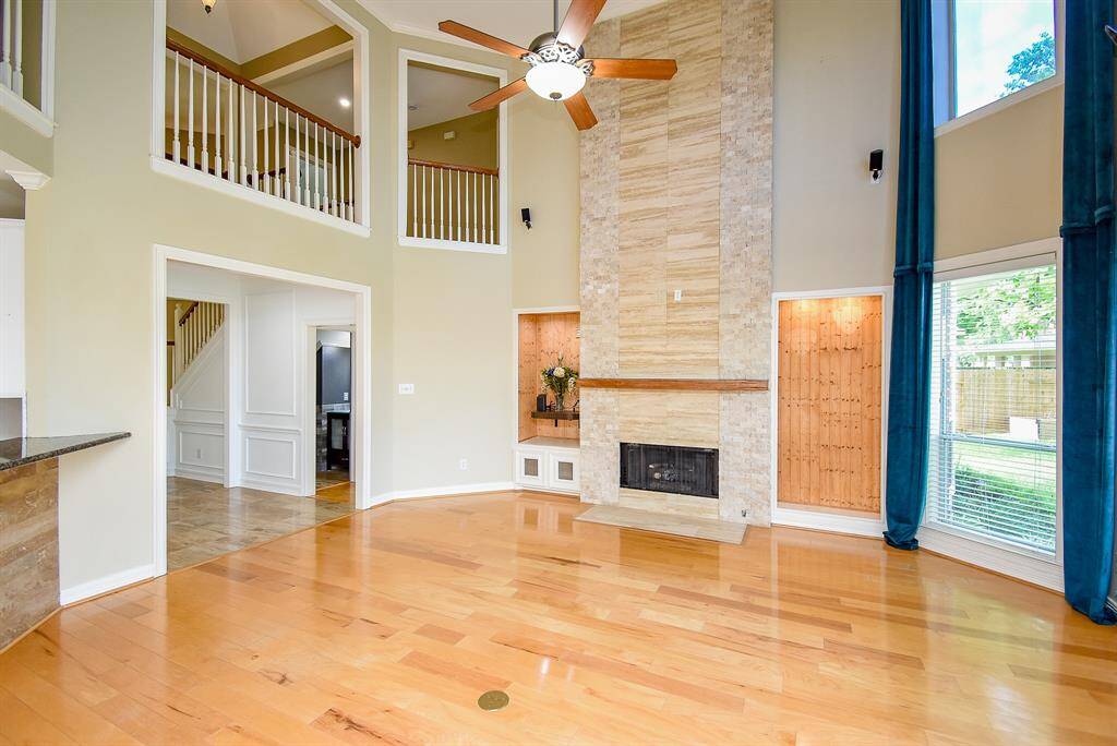 This grand room has multiple focal points such as the custom travertine and stacked rock fireplace wall along with a reclaimed wood mantel and gas logs in the fireplace.