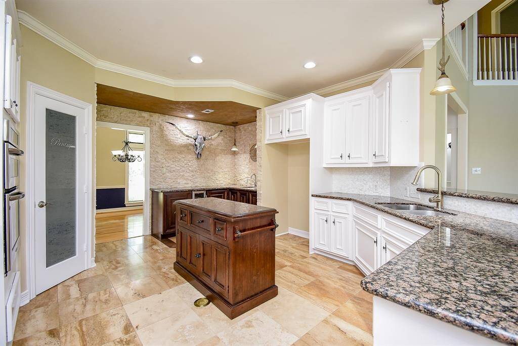 The rolling kitchen island can be moved into your preferred location. It has cabinet and drawer storage. An electrical outlet is recessed into the travertine for your convenience. The sellers replaced the original pantry door with a frosted glass door.