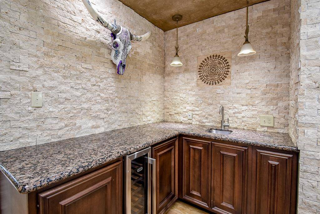 Custom built wet bar, coffee bar, and 18-bottle wine cooler.  Birch cabinetry built with 3 hidden drawers and stained walnut finish to complete kitchen additions plus gorgeous stack stone wall surround.