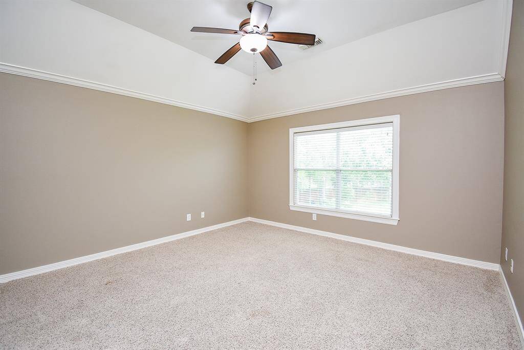 Secondary bedroom 2 shares views of the backyard, features crown molding, cove ceiling, a large walk-in closet and a dedicated vanity area!