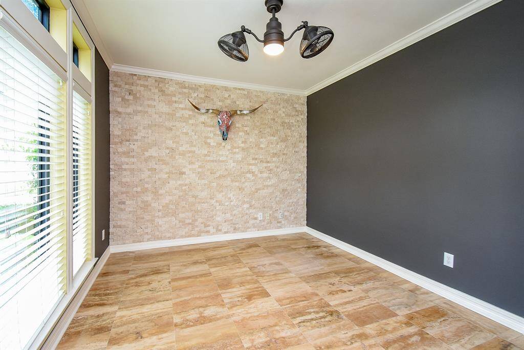 The travertine floors flow into the study which features a stacked rock wall and updated ceiling fan with fixture!