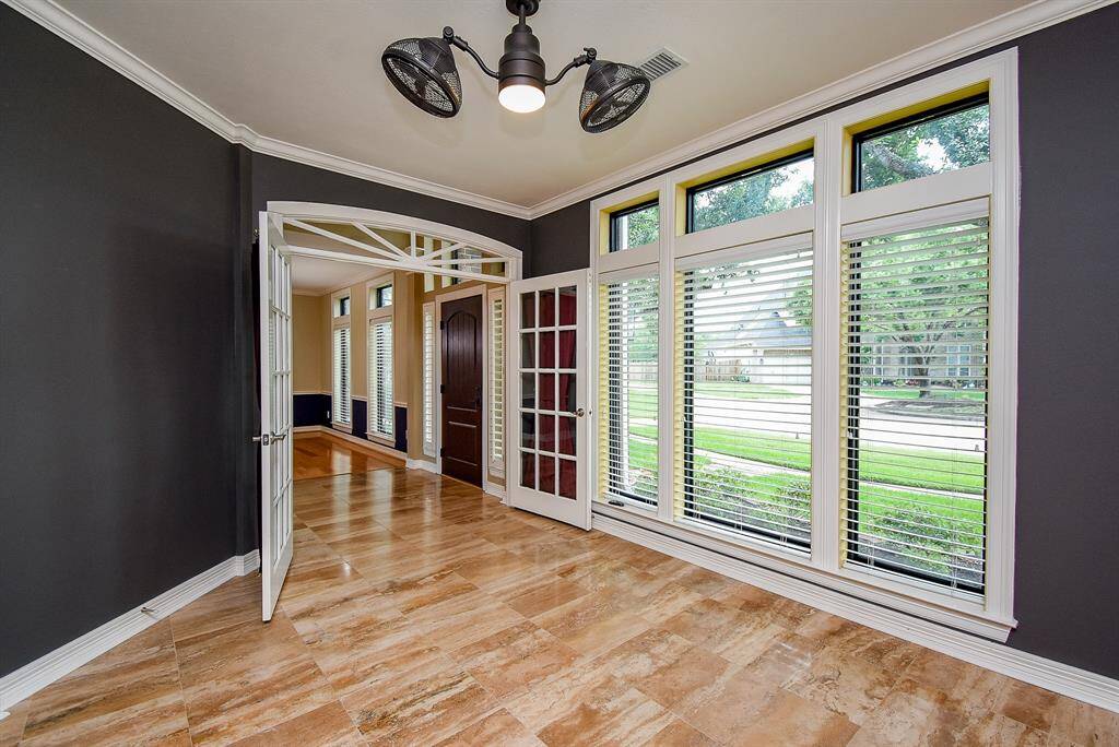 The study has French doors, a wall of windows and crown molding.