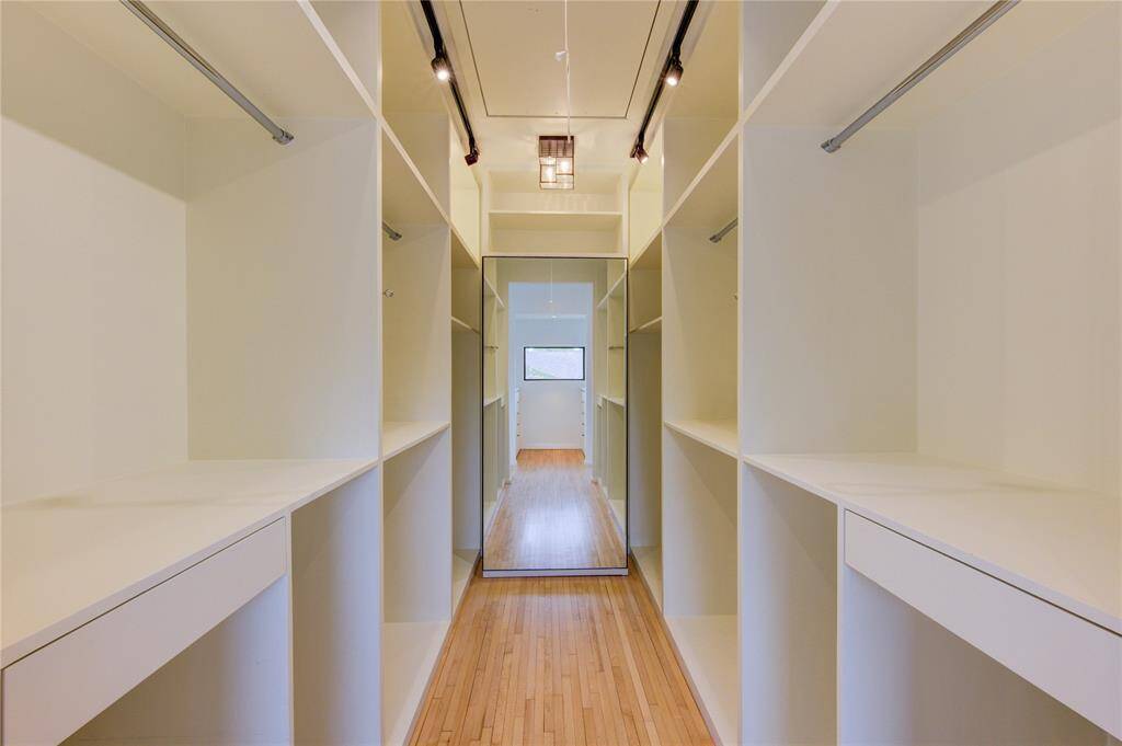 Spacious walk-in closet with ample shelving and elegant lighting, perfect for all your wardrobe needs.