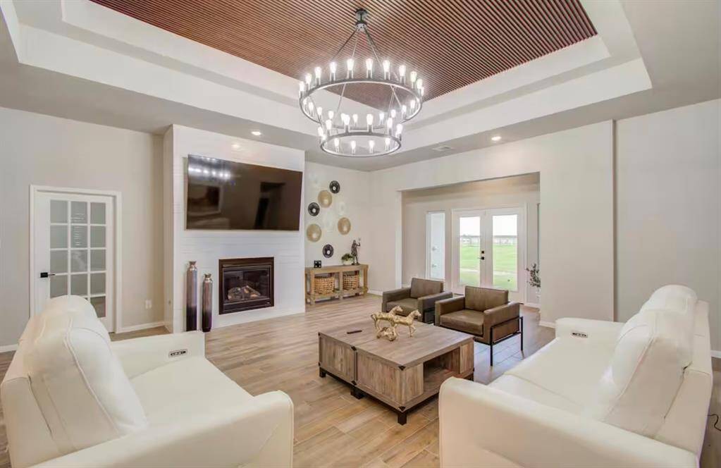 Living room features beautiful flooring, achandelier, high ceilings, fireplace, and access to the backyard.