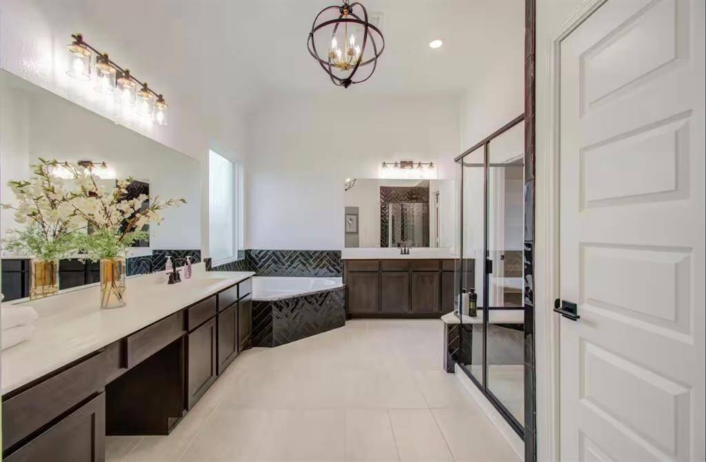 The primary bathroom features tile floors, dual sinks, vanity area, walk-in shower, and separate tub.