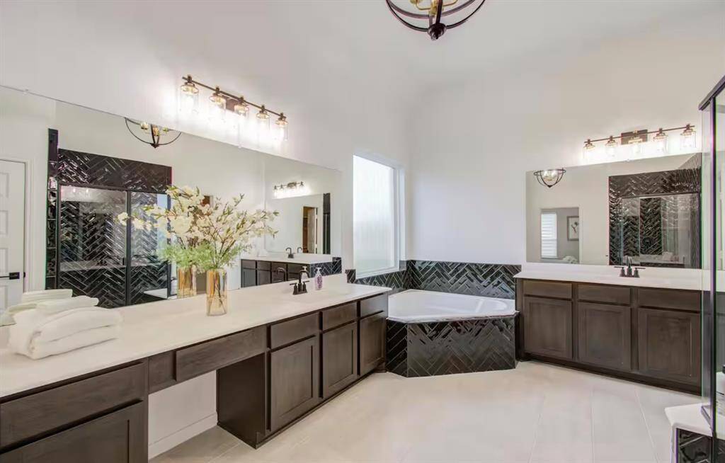 The primary bathroom features tile floors, dual sinks, vanity area, walk-in shower, and separate tub.