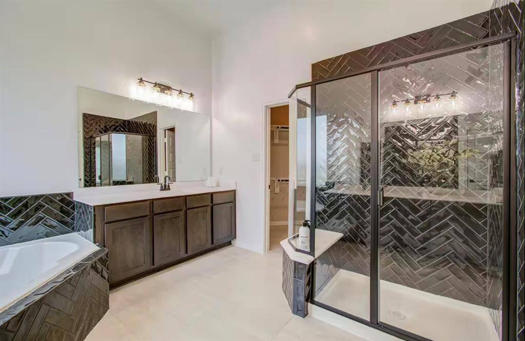 The spacious walk-in shower has tile surround, sitting area, and framed glass door.