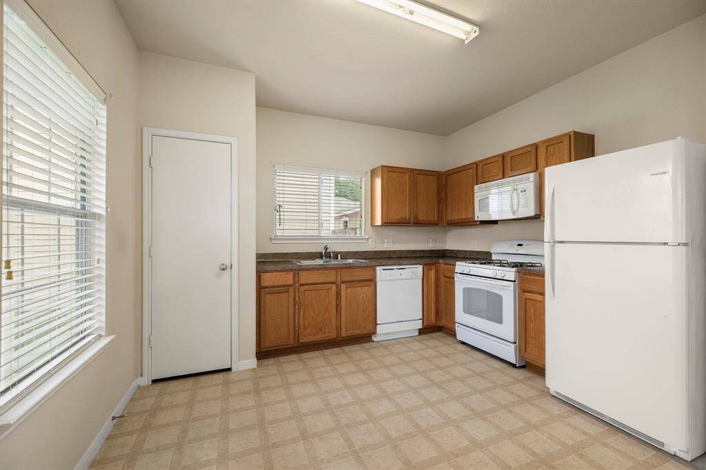 Inside the kitchen, a window overlooks the front porch, filling the space with natural light. The pantry is conveniently located to the left of the kitchen sink, and another window above the sink brightens the area. The kitchen comes equipped with essential appliances, including a refrigerator, gas range, built-in microwave, dishwasher, and garbage disposal, making it ready for all your cooking needs.