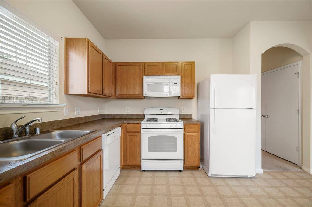 A closer look at the kitchen highlights the well-placed sink and appliances. Though the space is compact, there’s plenty of storage with cabinets and pantry access, making it both functional and efficient. The included appliances—refrigerator, gas range, built-in microwave, dishwasher, and garbage disposal—ensure you have everything you need to cook and entertain with ease.