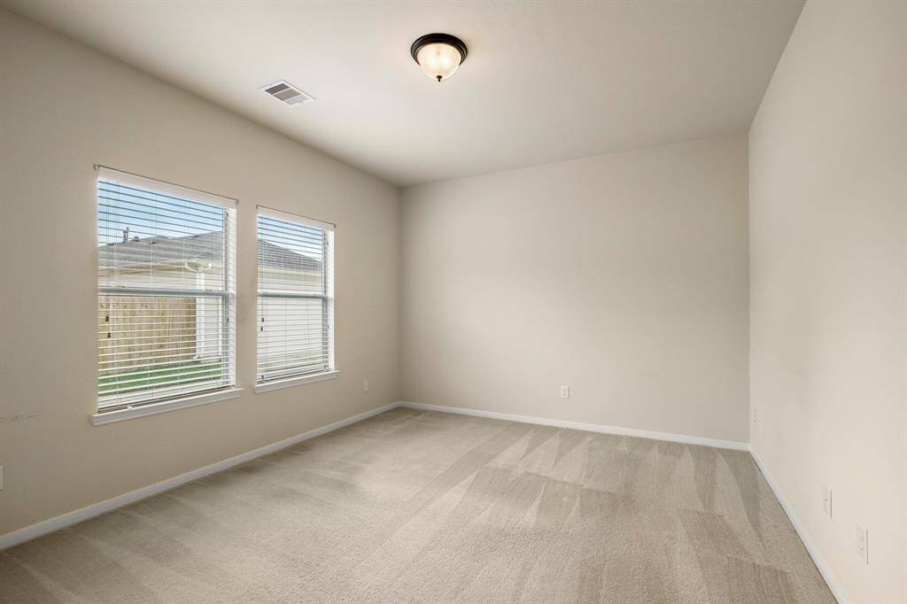 The primary bedroom features large windows that overlook the alley behind the home, offering plenty of natural light and a quiet, private view. It’s a peaceful space to unwind and enjoy the tranquility of the surrounding area.
