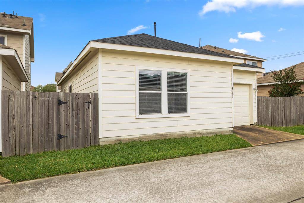 A view of the rear of the home from the alley reveals the gate leading to the side yard, offering easy access to the outdoor space. This practical feature enhances the home's flow and provides convenient entry to the private yard area.