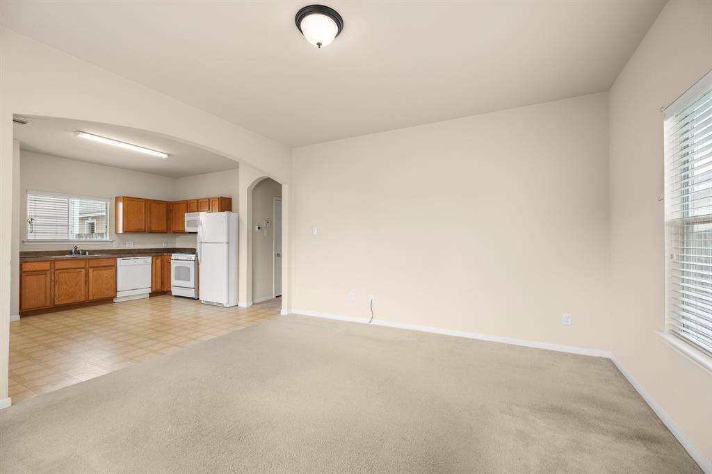 As you move into the living room, the open layout reveals a seamless flow into the kitchen. This spacious area offers a bright, airy feel, perfect for both everyday living and entertaining. The open design makes the space feel larger and more connected.