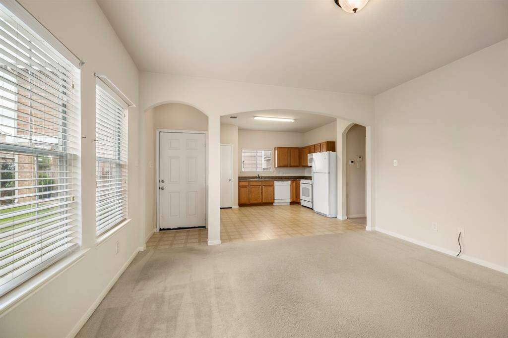 Looking back toward the front door, you'll notice charming arched openings that lead into the kitchen, creating a sense of openness. A separate archway near the front door adds a touch of architectural detail, forming a small foyer area that enhances the home's welcoming feel.
