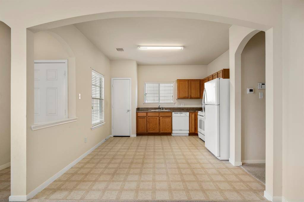 As you move toward the kitchen, you'll notice the front door to the left, offering easy access to the outside. To the right, a doorway leads down the hallway to the bedrooms, providing a convenient layout that keeps living and sleeping spaces well-separated for added privacy.