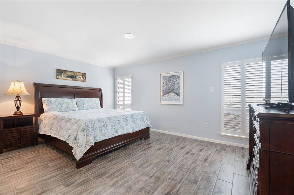 The primary suite is filled with natural light, thanks to large windows adorned with elegant plantation shutters. This serene retreat also includes a luxurious ensuite, offering both privacy and style.