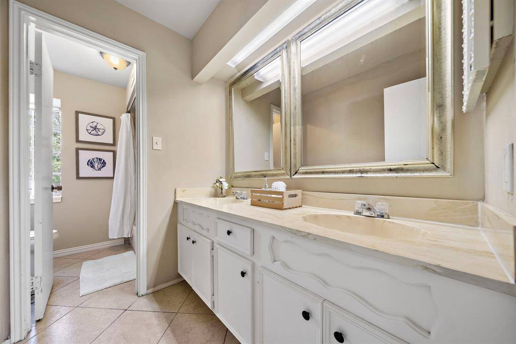 Hall bathroom with double sinks and a separate room housing the tub/shower combo.