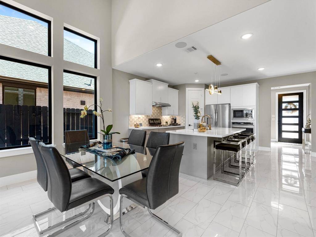 Sleek and modern  this space is highlighted by a large window  providing natural light and airy feel, boasting high end appliances, beautiful 2 tones cabinets and stylish backsplash, the island provide extra seating which adds functionality to the space, with luxury finishes and tones of upgrades this house is easy to maintain.