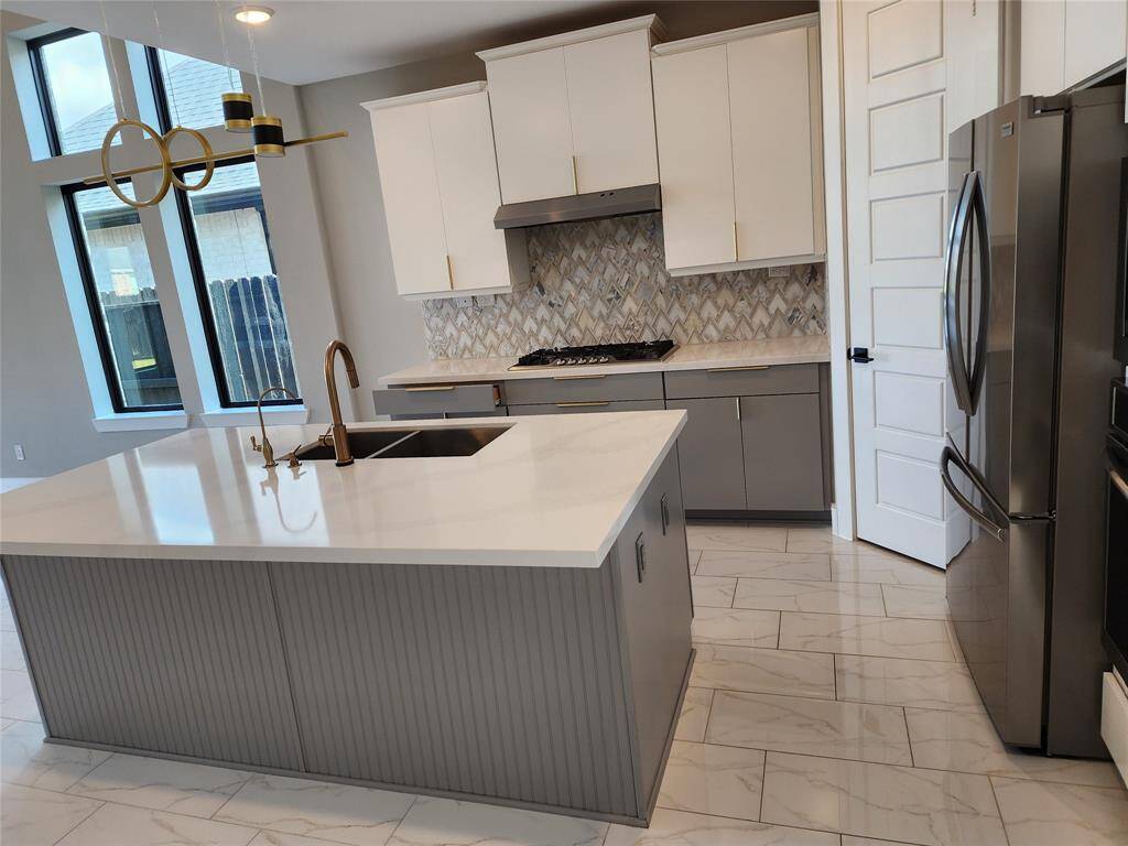 The kitchen have many details like hardware and 8 Ft  doors, the herringbone pattern on the back splash the combination of cabinetry, surrounded by double panel windows which are upgrades on this home in order to bring the modern aspect and allow the flow of the natural light.