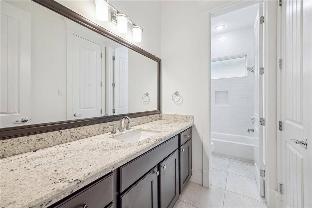 The separate bath and shower area features crisp white subway tile, a built-in niche for added convenience, and a frosted window that allows for natural light while maintaining privacy. Thoughtfully designed to accommodate multiple users, this bathroom serves the secondary bedrooms with both practicality and elegance.