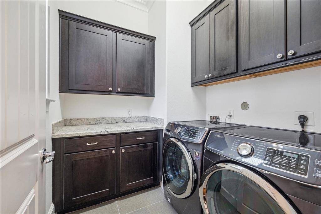 Designed for efficiency and organization, this second-floor laundry room offers everything you need to streamline household tasks. Sleek dark cabinetry provides plenty of storage for essentials, while the granite countertops create a functional folding and prep space.