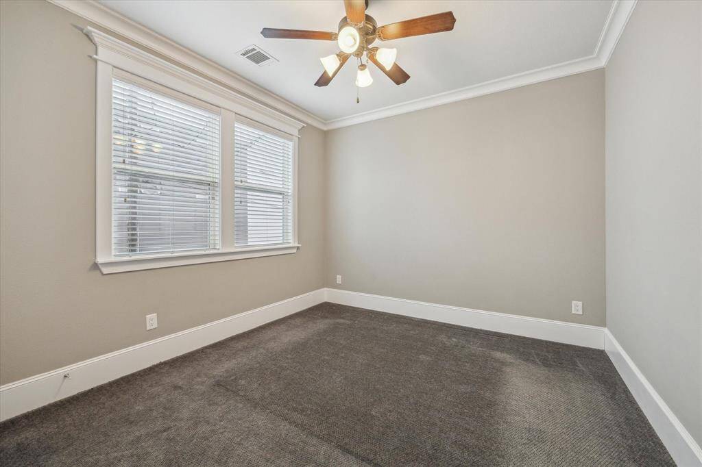 Tucked away for privacy, this garage apartment bedroom offers a peaceful retreat with neutral tones and plush carpeting. A large window allows for ample natural light, while crown molding and custom trimwork add a refined touch. The space is well-sized for a comfortable sleeping area or could serve as a quiet home office.