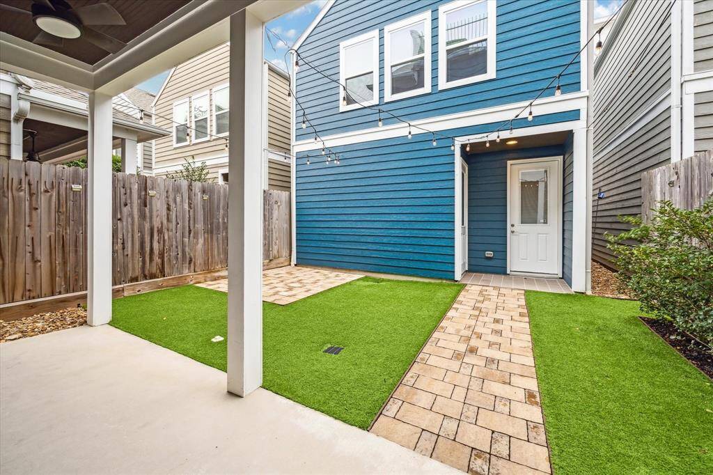 A beautifully designed backyard provides a welcoming pathway to the private garage apartment. The paved walkway, complemented by lush artificial turf, ensures easy access while maintaining a clean, low-maintenance outdoor space.