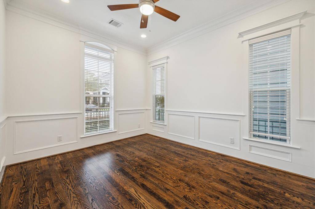 Just off the foyer, a flexible space with wainscoting and large windows is ideal for a home office or formal sitting area.