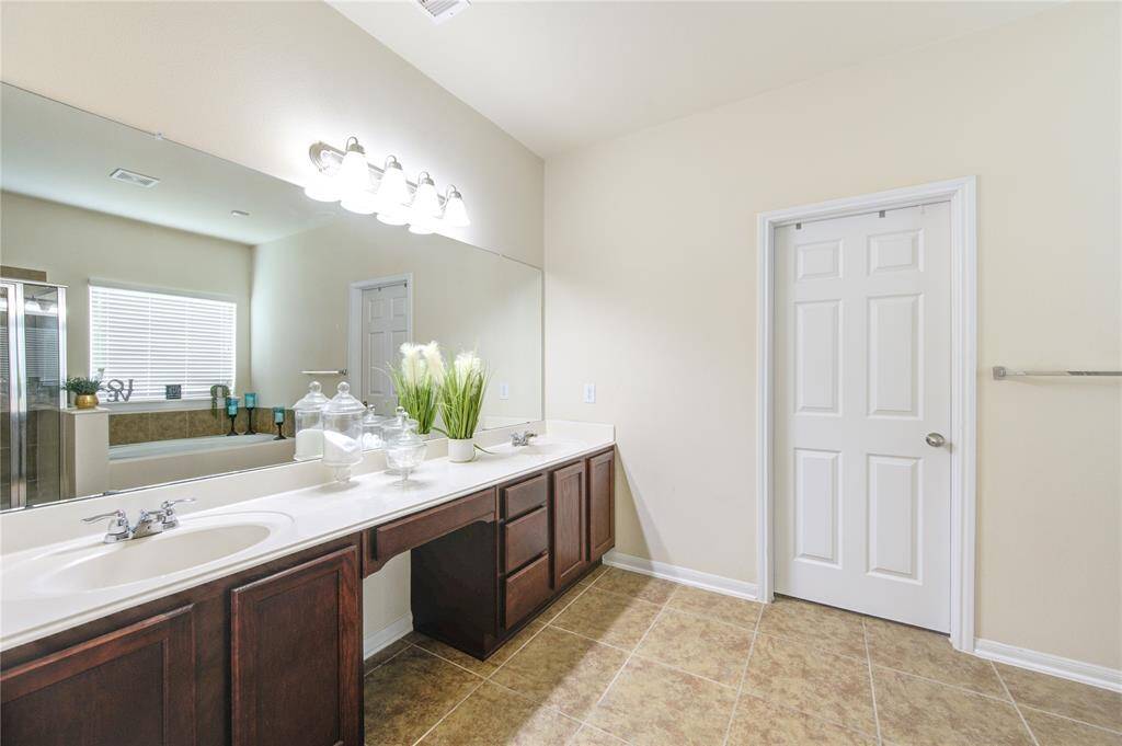 Primary bath with double sinks and vanity area with a large closet