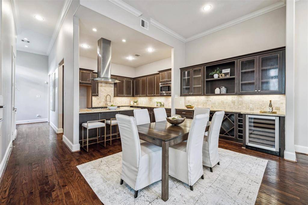 This home has a modern dining area with dark wood cabinetry, and a built-in wine cooler. The space is well-lit with recessed lighting and features hardwood floors and a neutral color palette.