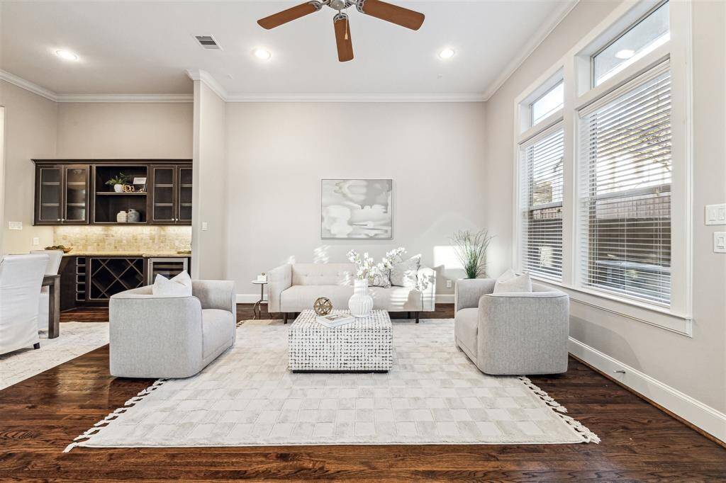 Another view of the living room featuring large windows, hardwood floors, cozy seating area, perfect for entertaining.
