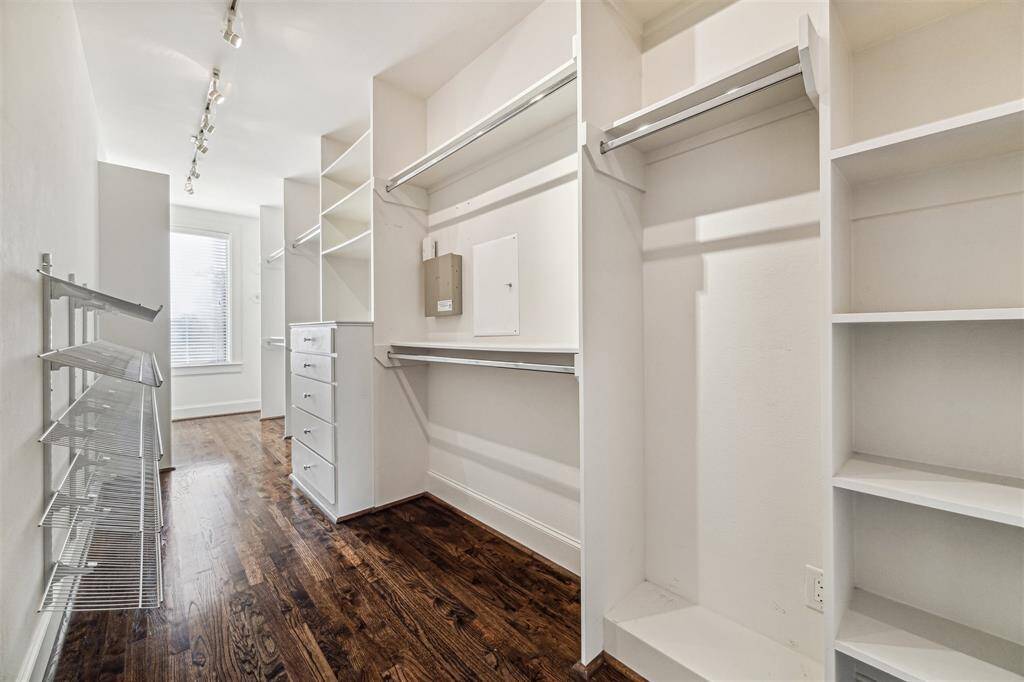 Spacious walk-in closet with hardwood floors, abundant shelving, and hanging space.
