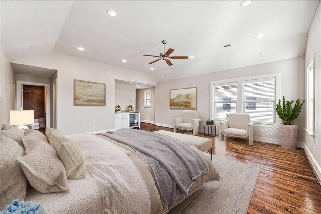 The third floor flex room being showcased as a spacious bedroom features hardwood floors, a ceiling fan, and ample natural light from large windows. It includes a cozy sitting area, neutral decor, and an ensuite bathroom, creating a serene and inviting atmosphere.