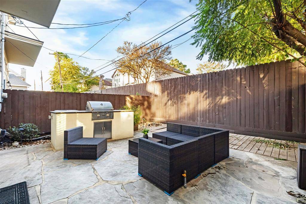 Cozy backyard with a stone patio, featuring a built-in grill and comfortable outdoor seating. Perfect for entertaining and relaxation.