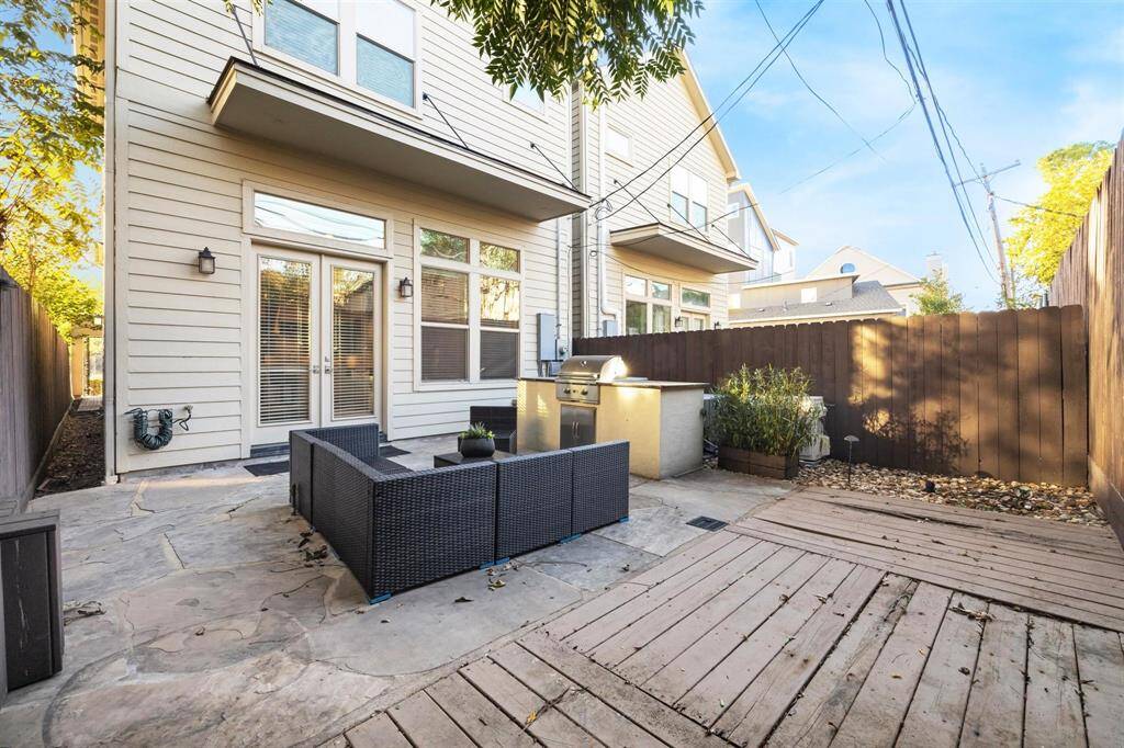 Another view of the patio, featuring a built-in grill, surrounded by a tall wooden fence for privacy. The space is ideal for entertaining and relaxing.