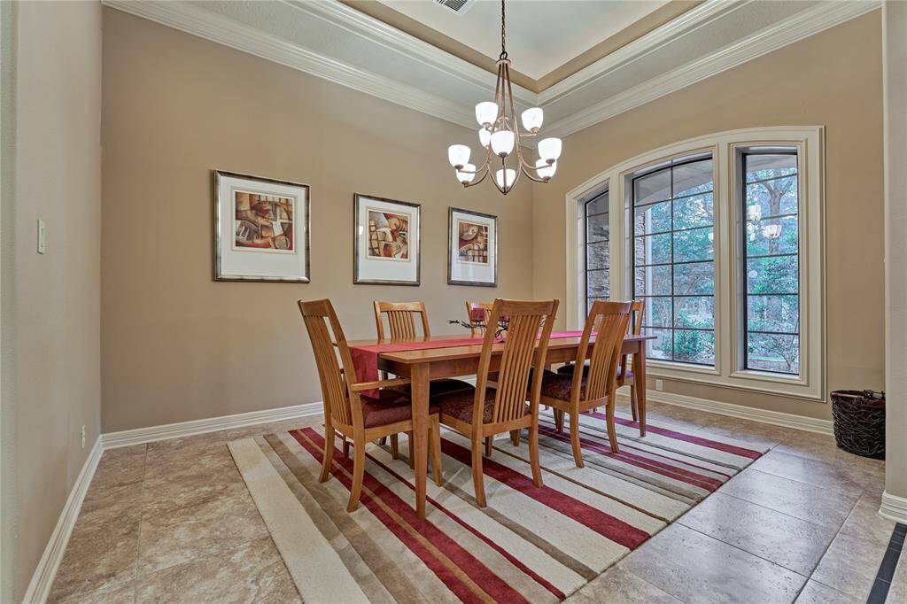 Spacious dining room with tiered ceiling, extensive crown molding and striking framework on the windows.