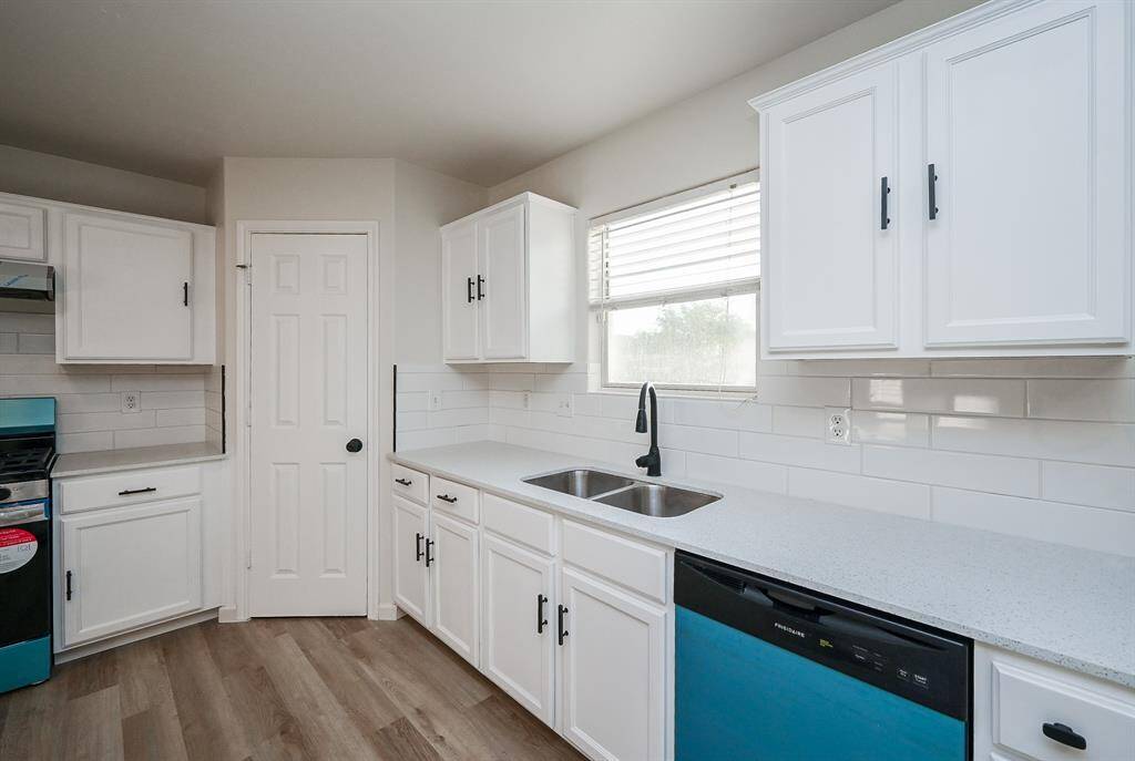 Modern kitchen with white cabinetry, light countertops, and stainless steel appliances. Features a double sink, ample storage, and bright natural light from the window.