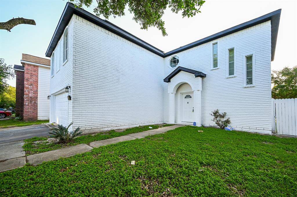 This home features a modern white brick exterior with a two-story design. It includes a welcoming arched entryway and a neatly maintained front lawn, offering a clean and inviting curb appeal.