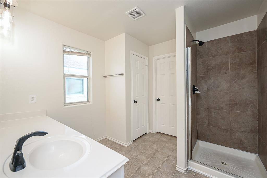 Spacious primary bathroom featuring a sleek standing shower with a glass door, modern fixtures, and ample natural light for a refreshing start to your day.