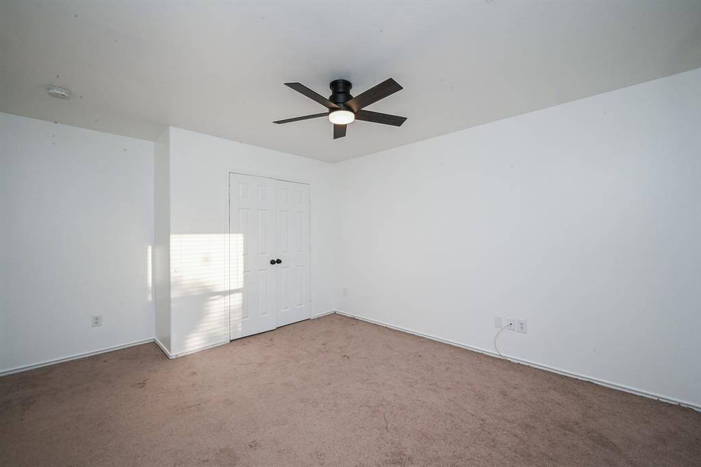 Spacious bedroom with modern ceiling fan, fresh white walls, and ample natural light. Ideal for creating your perfect retreat.