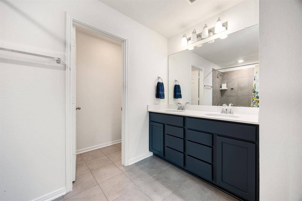 This primary bathroom is definitely move-in ready! Featuring a shower/tub combo custom tile detailing, dark cabinets with light countertops, spacious walk-in closet with shelving, neutral paint with sleek finishes.
