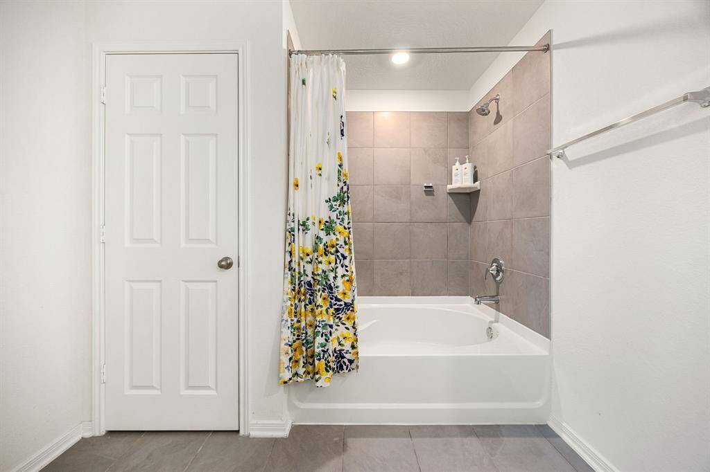 This additional view of the primary bath showcases a shower/tub combo with tile surround.