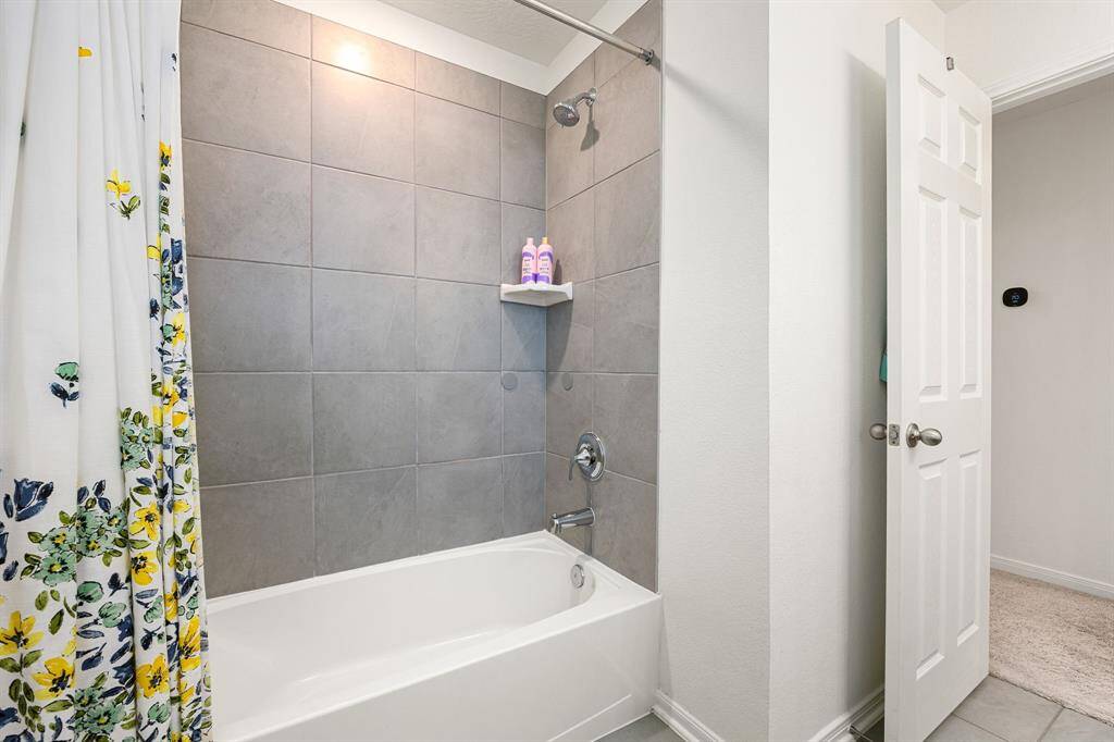 This additional view of the primary bath showcases a shower/tub combo with tile surround.