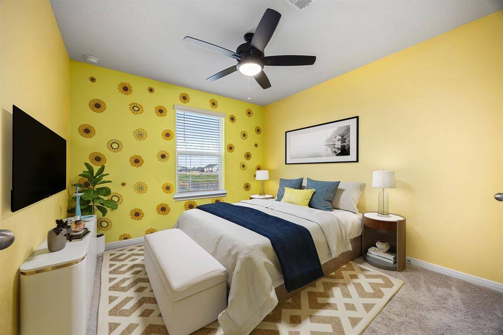 Secondary bedroom features plush carpet, custom paint, dark stained ceiling fan with lighting and a large window with privacy blinds. *virtual staging*