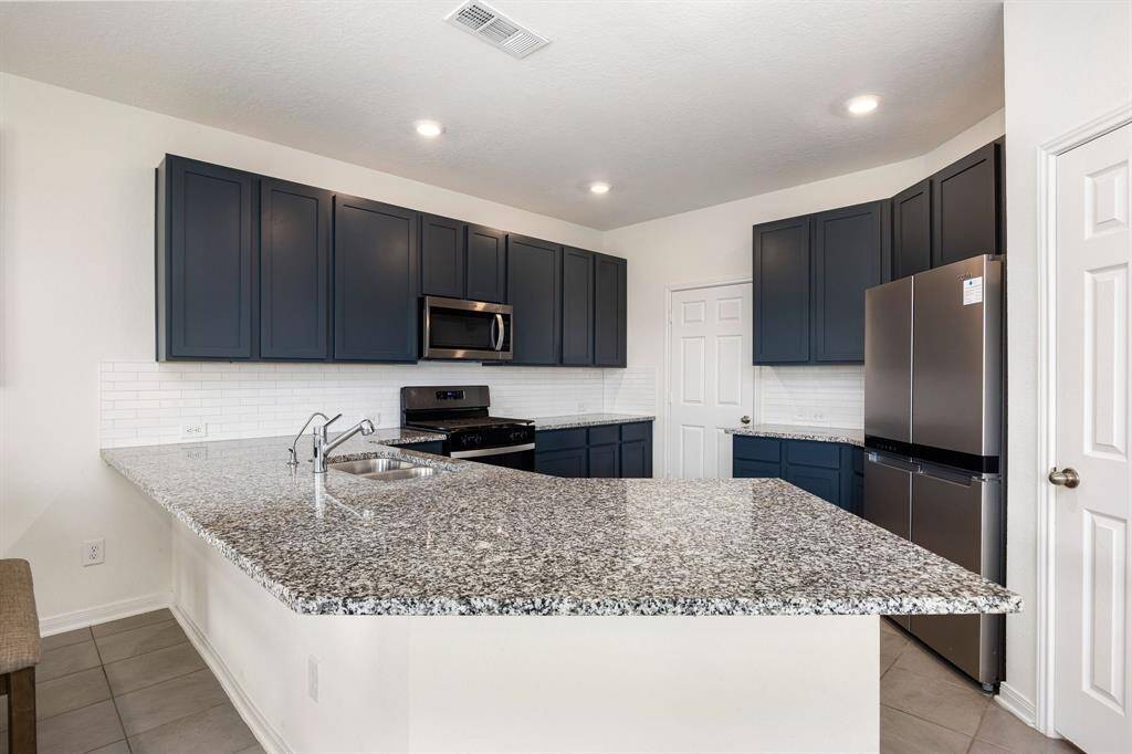This stunning kitchen displays such a beautiful contrast with the dark cabinets, neutral paint, granite countertops, light modern backsplash, and SS appliances, oversized kitchen bar with extra storage, breakfast bar, recessed lighting and walk in pantry.